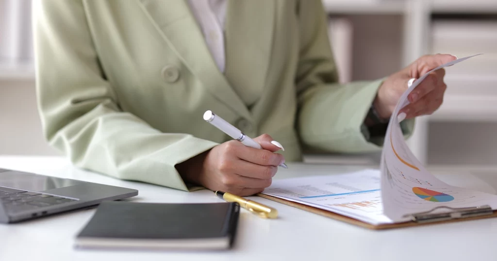 Femme en blazer vert clair analysant un audit comptable