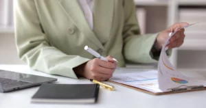Femme en blazer vert clair analysant un audit comptable