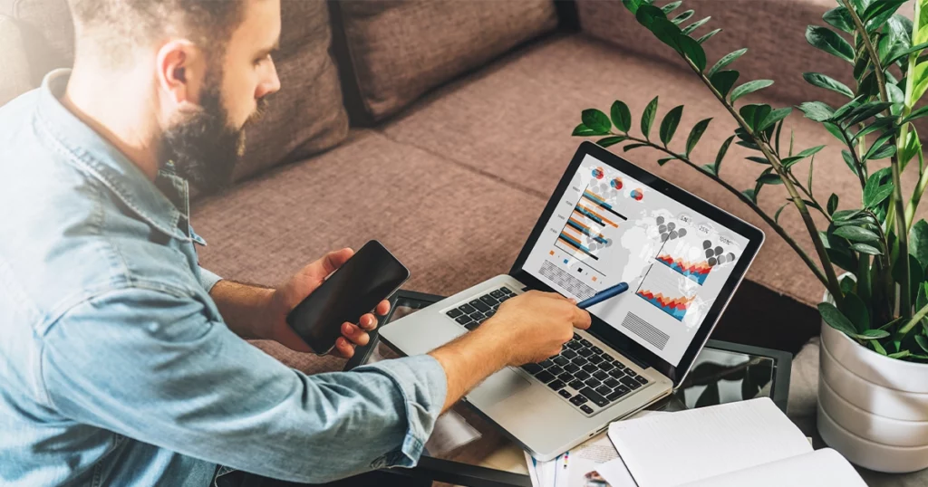 Homme consultant des graphiques financiers sur ordinateur pour identifier des déductions fiscales pour PME