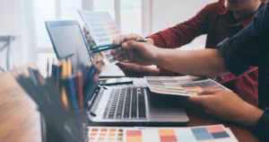 Des professionnels analysent des supports visuels et des données devant un ordinateur en agence de communication