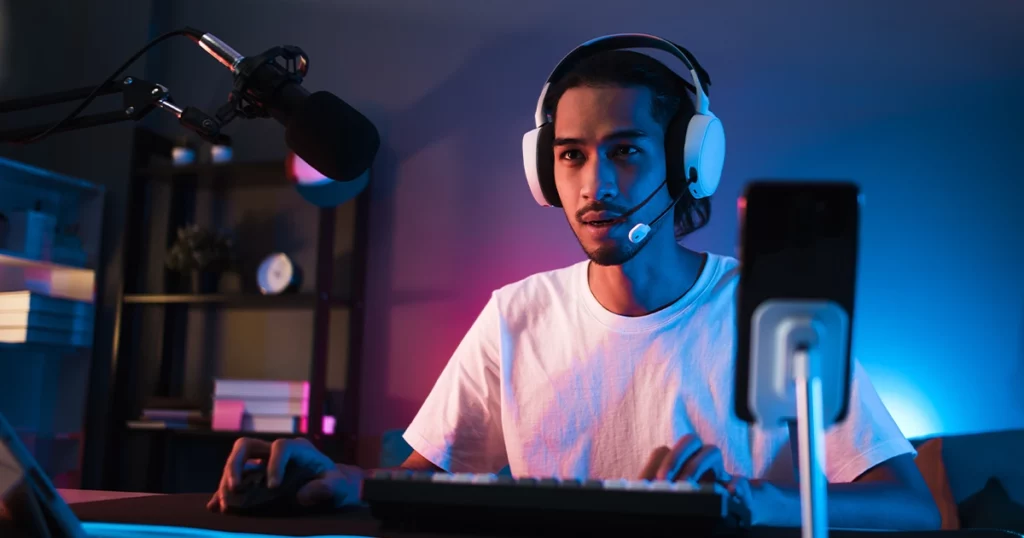 Un streamer portant un casque micro en live devant son ordinateur et sa caméra