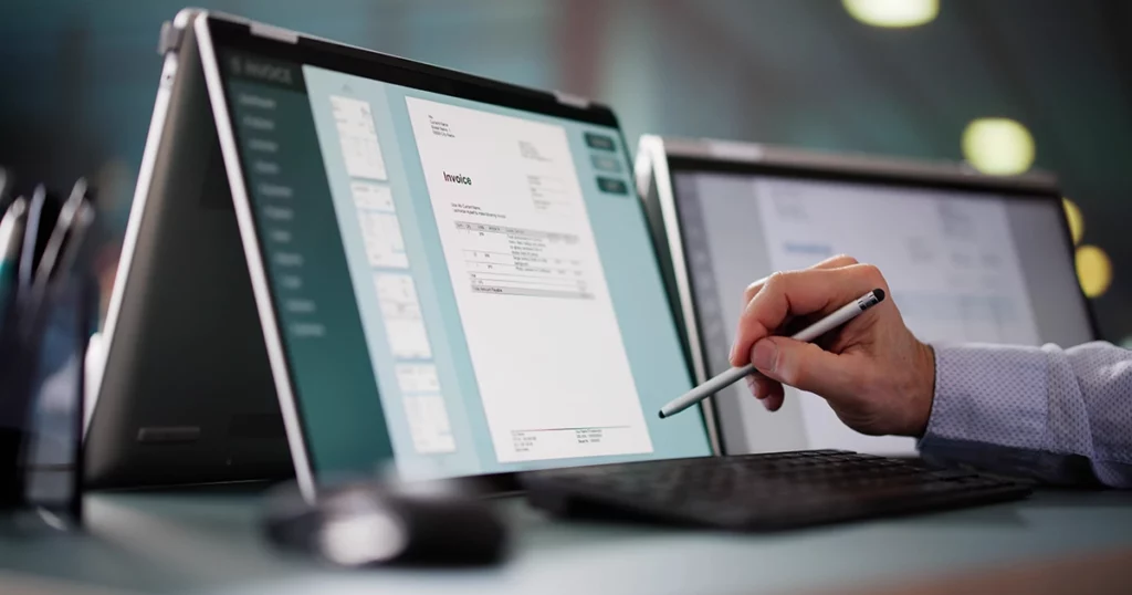 Professionnel consultant une facture électronique sur tablette avec stylet dans un environnement de travail moderne