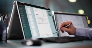 Professionnel consultant une facture électronique sur tablette avec stylet dans un environnement de travail moderne