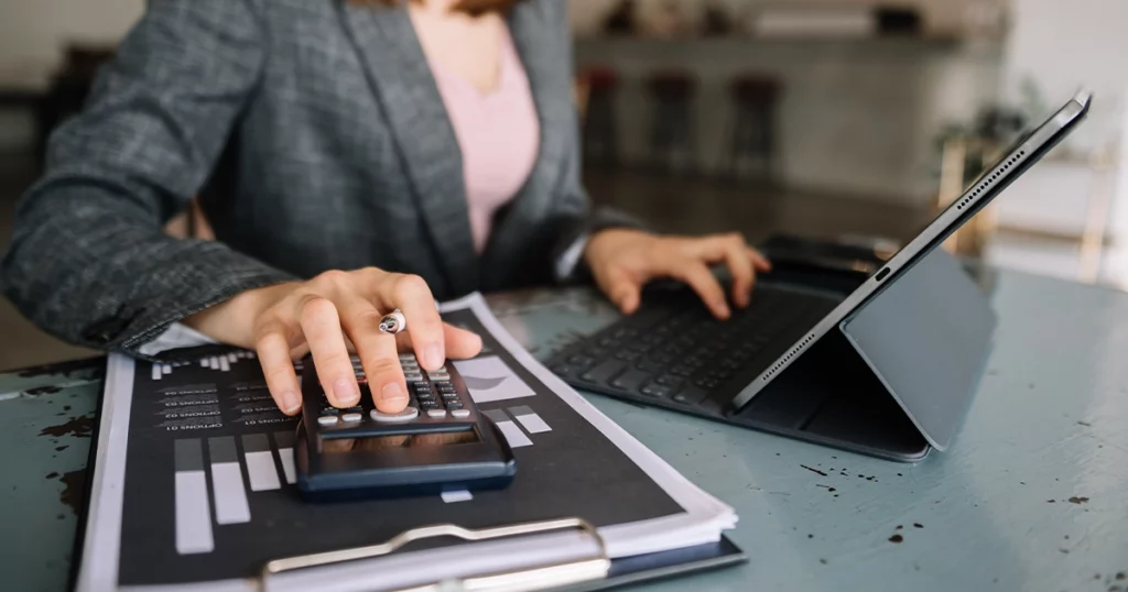 Comptable analysant des données financières en temps réel avec calculatrice et tablette pour optimiser le pilotage via la facture électronique