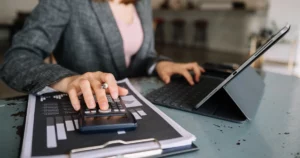Comptable analysant des données financières en temps réel avec calculatrice et tablette pour optimiser le pilotage via la facture électronique